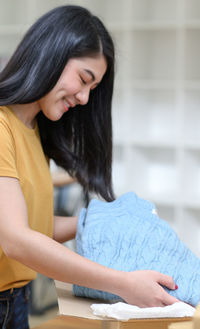 A woman is packing a sweater in a box for shipping.