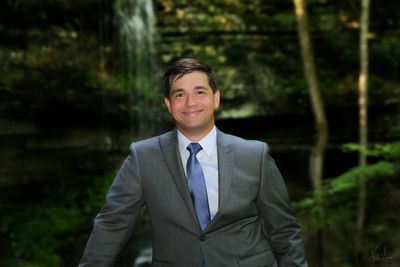 Portrait of smiling man in suit standing against trees