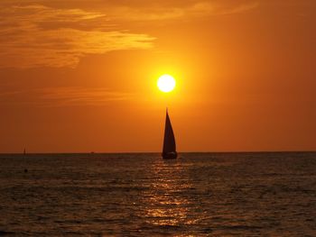 Silhouette sailboat in sea against sky during sunset