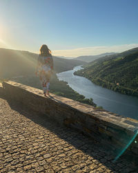 Rear view of woman standing on mountain against sky