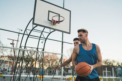 Men playing basketball against sky