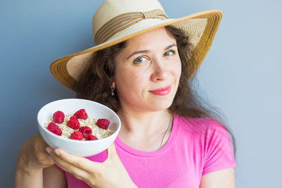 Portrait of woman holding ice cream against white background