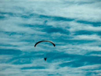 Low angle view of person paragliding against sky