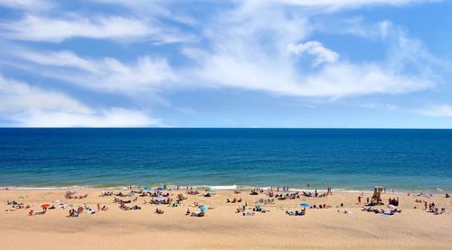 Group of people on beach against blue sky