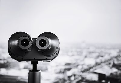 Close-up of coin-operated binoculars against cityscape