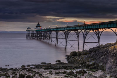 Bridge over sea against sky during sunset