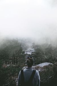 Rear view of woman looking at forest during foggy weather