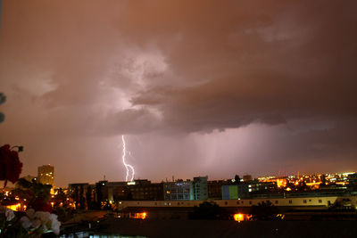 Panoramic view of lightning over buildings in city at night