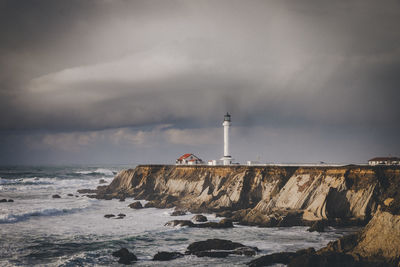 Lighthouse by sea against sky