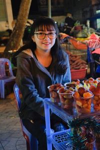 Portrait of smiling teenage girl selling fruits in glass