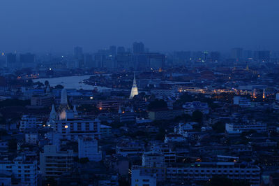 High angle view of illuminated city against sky at dusk