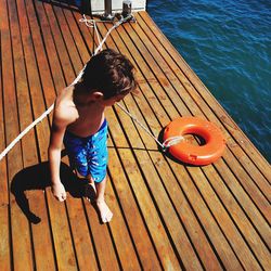 High angle view of boy pulling life belt while walking on pier