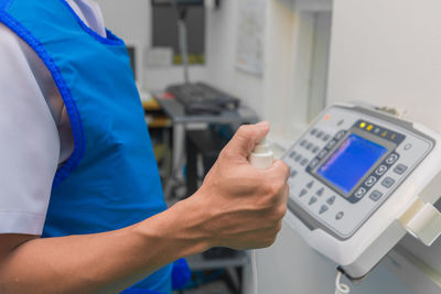 Midsection of doctor holding medical equipment at hospital