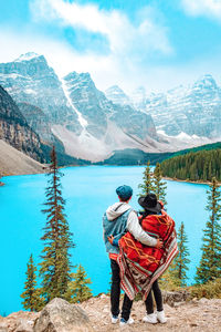 Rear view of men looking at mountains against sky