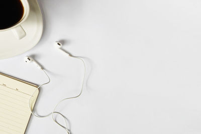 Top view of white workplace with coffee and earphone on it