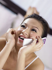 Close-up of happy woman talking on mobile phone in bedroom