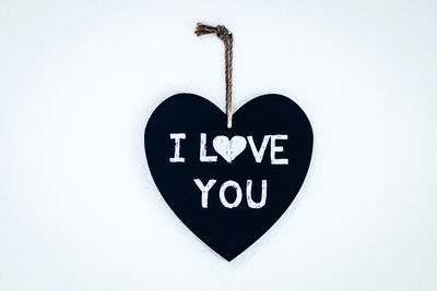 Close-up of heart shape sign hanging on white background