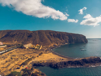 Aerial view of sea by land against sky