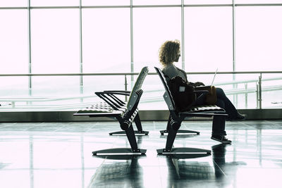 Rear view of woman sitting on chair at airport