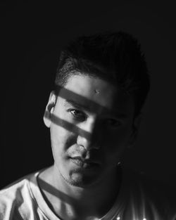 Close-up portrait of young man against black background