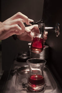 Cropped hands of man filling water in glass at darkroom