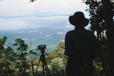 Rear view of man photographing on landscape against sky