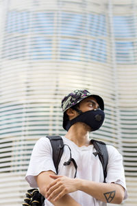 Man wearing a face mask to avoid coronavirus infection looking side ways while wearing a bucket cap.