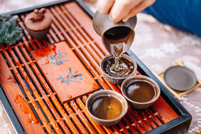 Close-up of hand pouring tea from pitcher on table