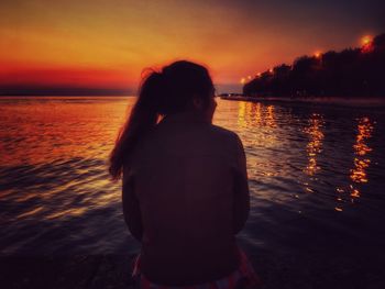 Rear view of silhouette man on beach at sunset