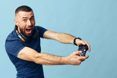 Portrait of young man holding camera against blue background