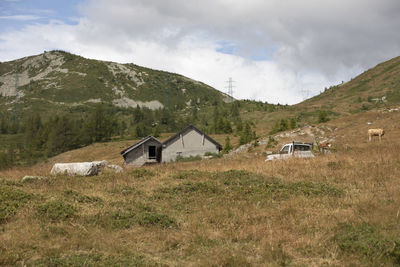 Houses on field by mountains against sky