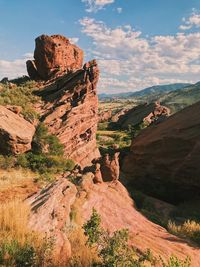 Rock formations on landscape against cloudy sky