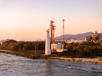 Lighthouse by sea against sky during sunset