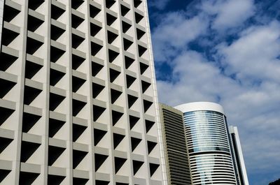 Low angle view of modern building against cloudy sky