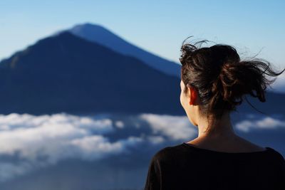 Rear view of woman looking at mountain against sky