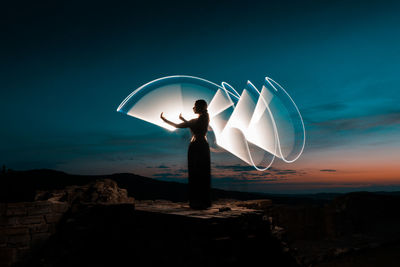 Digital composite image of woman holding umbrella against sky