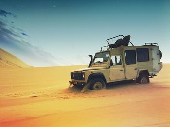 Sports utility vehicle on desert against sky