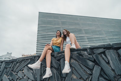 Young couple sitting against sky