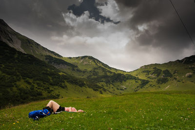 Man lying down on land against sky