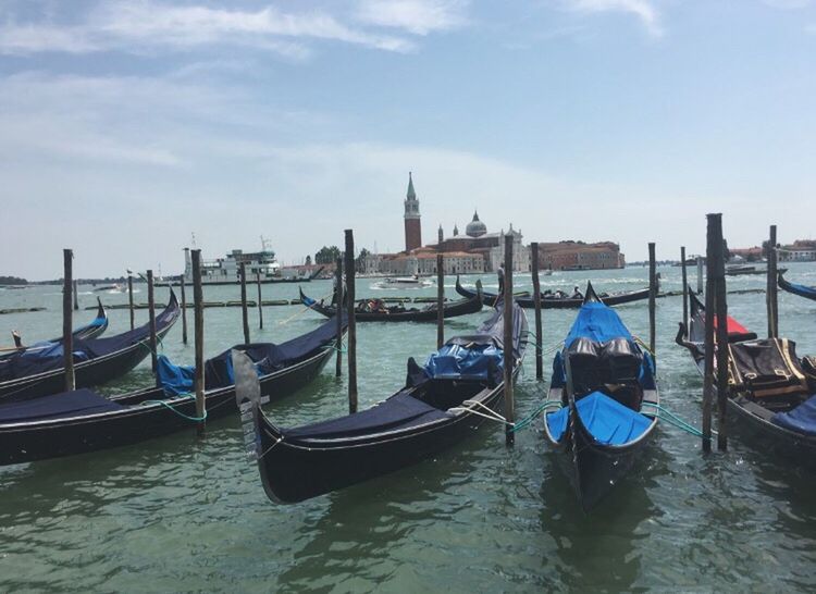 nautical vessel, boat, transportation, water, moored, mode of transport, architecture, city, waterfront, building exterior, gondola - traditional boat, travel destinations, river, built structure, sky, international landmark, tourism, famous place, culture, church, canal, day, in front of, bell tower - tower, tranquility, capital cities, cloud - sky