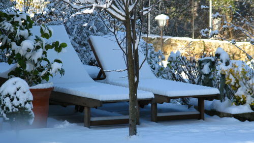 Snow covered deck chairs in yard