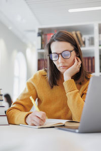 Young woman using laptop while sitting on table