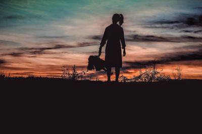 Silhouette man standing on field against sky during sunset