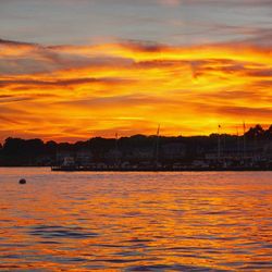 Scenic view of lake against dramatic sky during sunset
