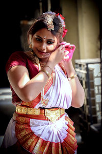 Woman in traditional clothing wearing earring at home