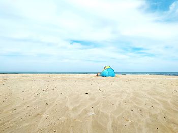 Rear view of man sitting on beach against sky