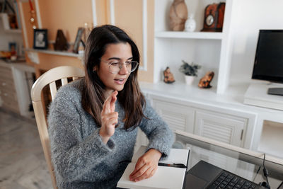 Young woman using phone while sitting on table