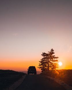 Silhouette car on road against sky during sunset