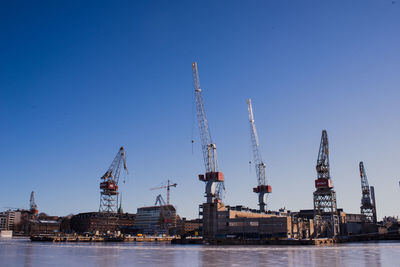 Cranes at a dock against clear blue sky