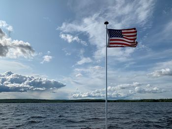 Flag sign by sea against sky